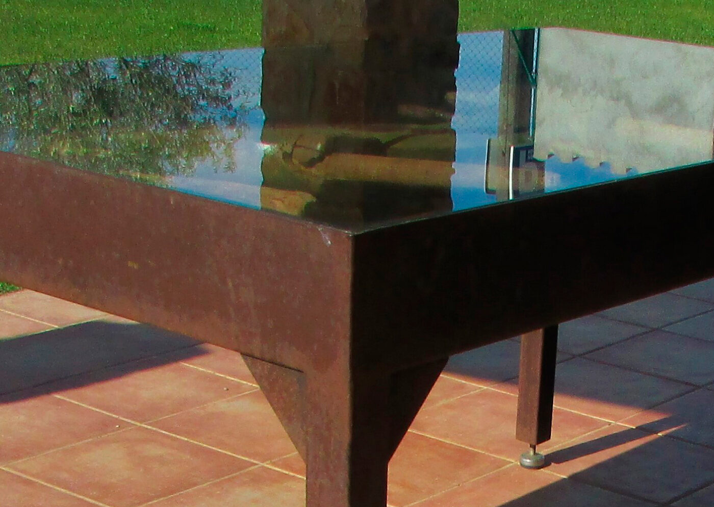 Mesa de exterior elegante en estructura de forja con superficie de vidrio