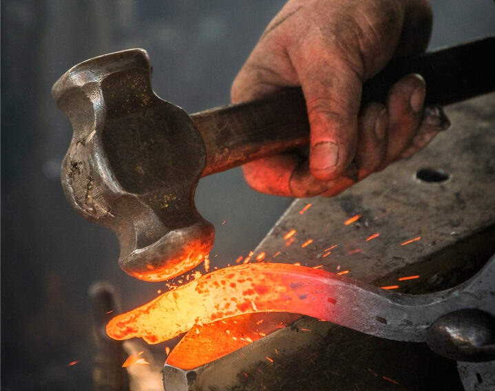 Obrero experto trabajando en un yunque en taller de herrería